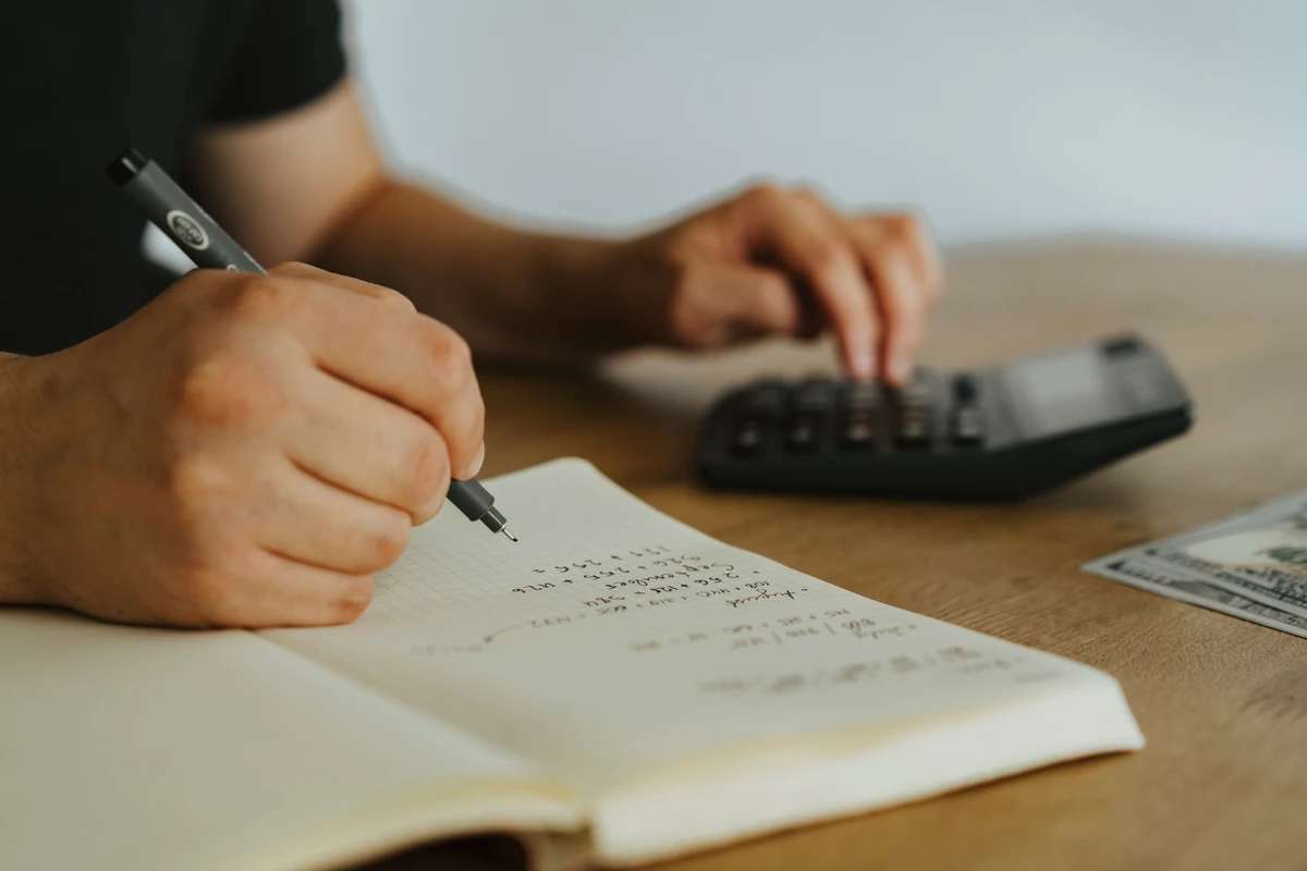 Business owner calculating tax filings with a calculator and notebook ahead of DIAN tax deadlines Colombia 2026